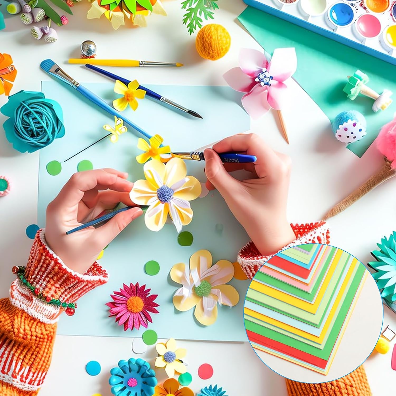 Colorful handmade paper flowers, paintbrushes and craft materials arranged on a creative workspace